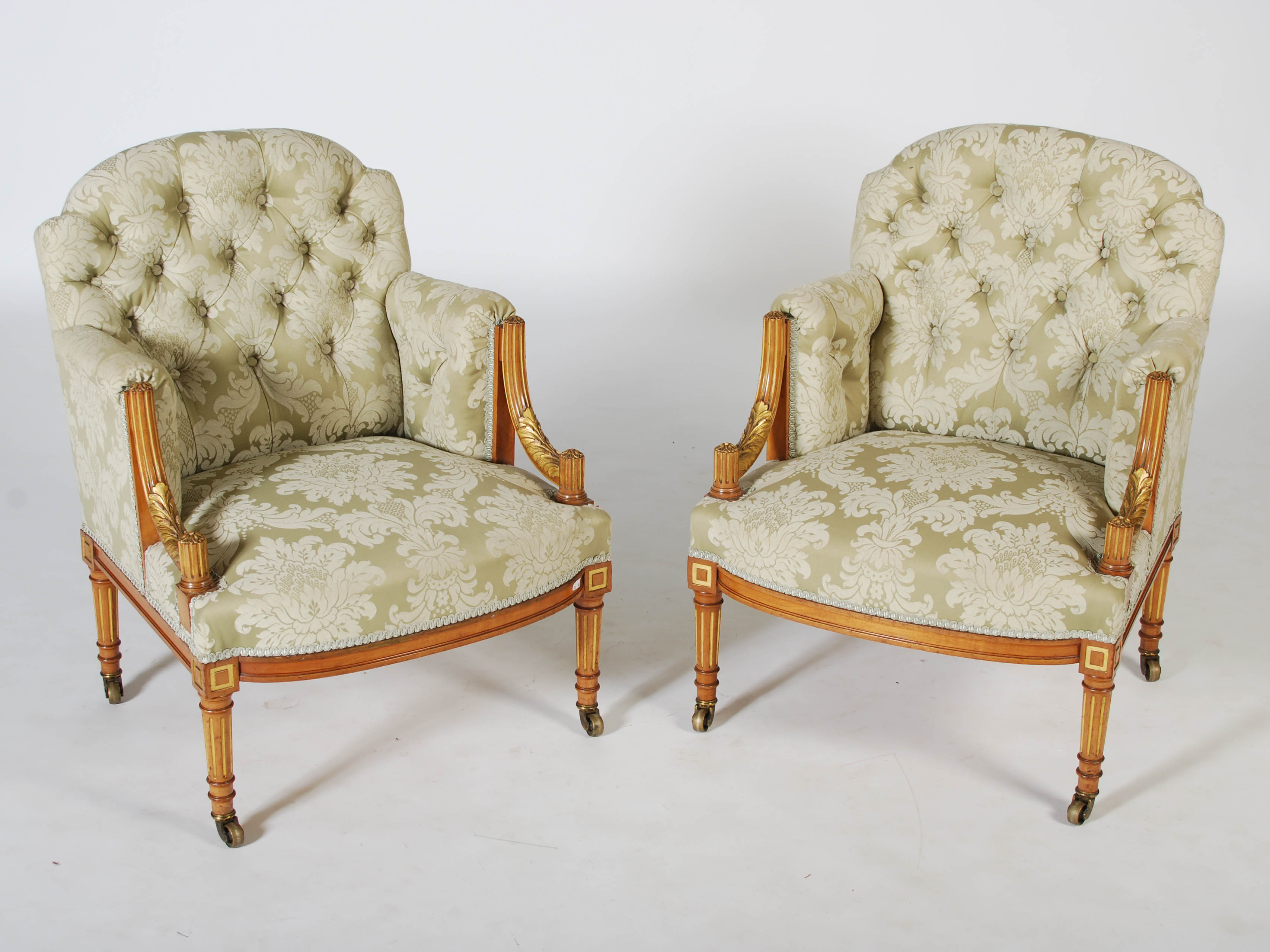 A pair of Edwardian mahogany and parcel gilt tub chairs, the button down upholstered backs, arms and