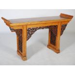 A Chinese elm wood altar table, the rectangular top with scroll carved ends, raised on two