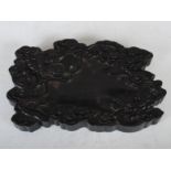 A Chinese ink stone, Qing Dynasty, carved from a heavy and dense dark wood, decorated in relief with