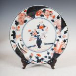 A Japanese Arita porcelain plate, decorated with a vase issuing peony within a border of