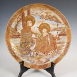 A Satsuma pottery charger, Meiji Period, decorated with lohan and children within a richly gilded