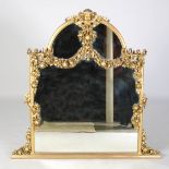 A late 19th century gilt wood overmantel mirror, the arched top centred with a putti head suspending
