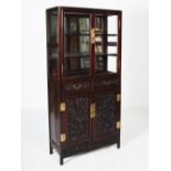 A Chinese dark wood mirror back display cabinet, the upper section with a pair of glazed cupboard