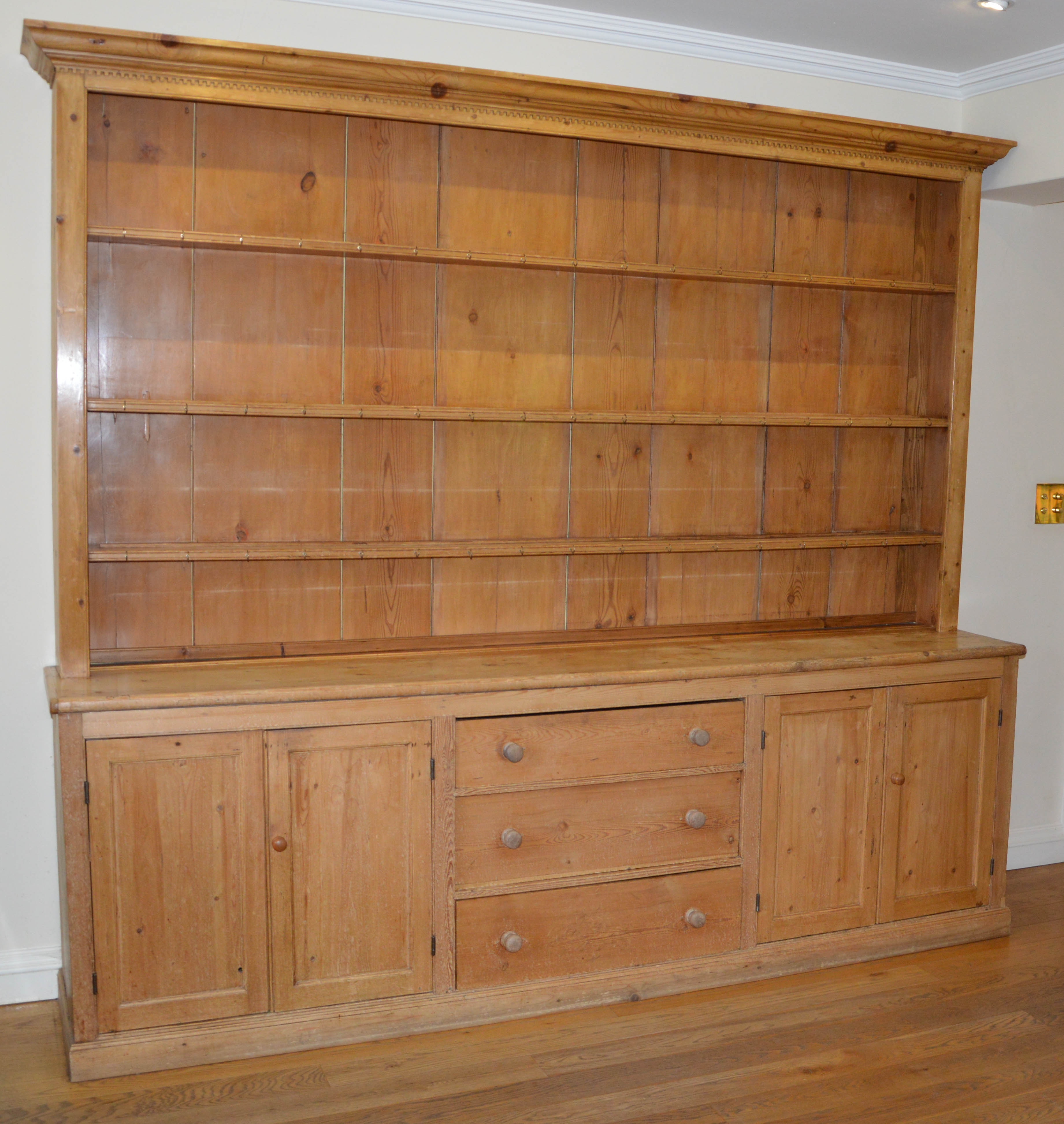 A late 19th/early 20th century pine country house kitchen dresser, the upper section with moulded