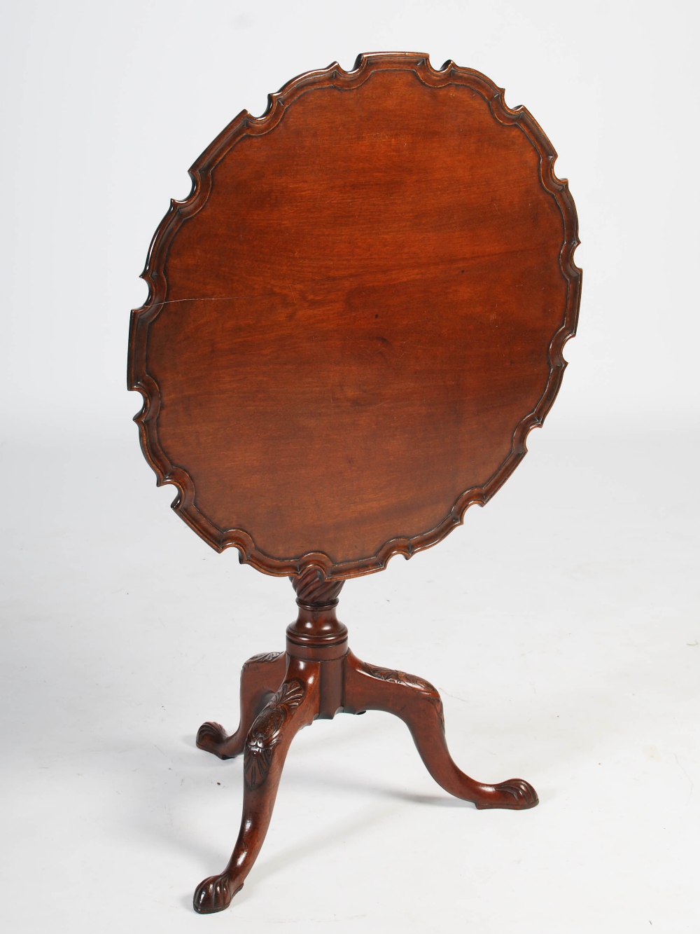 A George III mahogany occasional table, the hinged circular top with a pie-crust edge raised on a