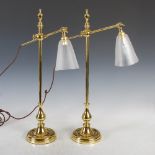 A pair of early 20th century brass table lamps, with two way adjustable arms supporting frosted