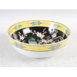 A Japanese black ground porcelain bowl, decorated with a prunus branch supporting long tailed bird