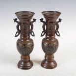 A pair of Japanese bronze twin handled vases, decorated in relief with flowers and birds, with