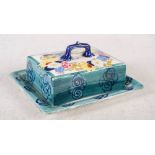 A Bough pottery green ground butter dish and cover, decorated with colourful flowers, signed E.A.