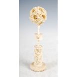 A Chinese ivory puzzle ball on stand, Qing Dynasty, the puzzle ball carved with dragons and scrolls,