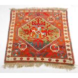A small Kazak rug, the madder ground centred with a green ground lozenge shaped medallion within a