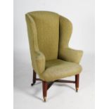 A 19th century George III style mahogany wing armchair, upholstered all over in green floral fabric,