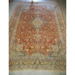 A large 20th century Persian rug, the madder ground centred with a blue ground medallion enclosing