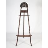 A Chinese dark wood easel, carved and pierced with prunus blossom, with two open shelves, 205cm high