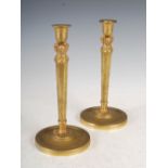 A pair of gilt metal Empire style candlesticks, the urn shaped nozzles supported by three