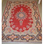 A Kirman carpet, the madder ground centred with a large floral medallions within a blue ground