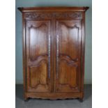 A 19th century French oak armoire, with foliate carved frieze and two cupboard doors.