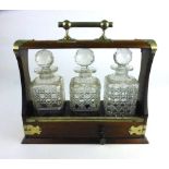 An early 20th century oak cased tantalus with silver plated mounts and three cut glass decanters, h.