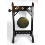 A late Victorian oak Gothic inspired dinner gong, with leather headed, bamboo handled hammer, h.