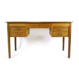 A Danish oak and crossbanded desk with an arrangement of five drawers on circular tapering legs, l.