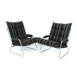 A pair of chromed tubular lounge armchairs with loose cushions
