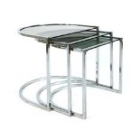 A 1970's nest of three semi-circular tables, the chromed frames supporting smoked glass surfaces,