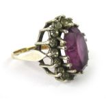 A 9ct yellow gold and silver dress ring set oval purple coloured glass within a border of clear