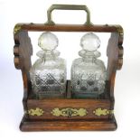 An early 20th century oak and brass mounted two decanter tantalus with fall front locking mechanism,