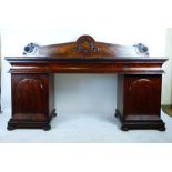 A William IV mahogany twin pedestal sideboard with carved laurel wreath to back above one long and