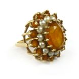 A 9ct yellow gold dress ring set oval orange coloured stone within a border of small pearls and