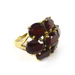 A 9ct yellow gold dress ring set seven oval red coloured stones in a flowerhead setting,