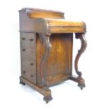 A Victorian walnut Davenport with concealed stationery section to top over lift up lid revealing