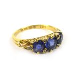 An 18ct yellow gold ring set three graduated sapphires and diamond chips within a scrollwork