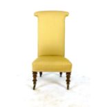 A Victorian rosewood nursing chair in pale gold upholstery on turned front legs with brass cup