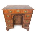 An early 18th century and later walnut knee hole desk the book matched and cross banded top over