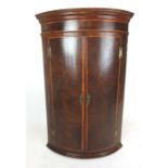 A late 18th century and later mahogany and satinwood banded bow front corner cupboard,