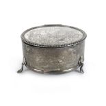 A George V silver jewellery container with an engraved surface, padded interior and three feet,