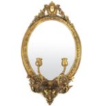 A 19th century oval gilt framed mirror with candle sconces in the Baroque style, h. 72 cm, w.