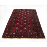 A hand woven Persian rug with multi lined border enclosing a red ground field with a geometric