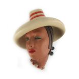 An Art Deco-type pottery wall plaque modelled as a lady wearing a red hat by Ian Douglas, Rd. N.