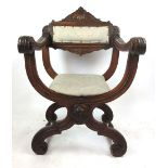 An early 20th century walnut x framed throne chair, profusely carved with blue floral upholstery, h.