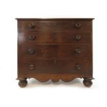 An early Victorian mahogany chest of four long graduated drawers with a shaped apron and turned