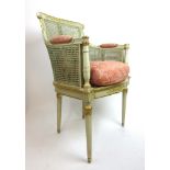 An early 20th century grey painted and parcel gilt bergere arm chair with pink fabric upholstered