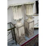 URNS ON STANDS, a pair, in metal in a distressed cream painted finish, 125cm H.