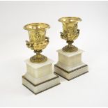 CLASSICAL URNS, a pair, in the Grand Tour manner, gilt metal, each on a stepped marble plinth,