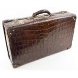 SUITCASE, late 19th century crocodile leather with brass locks and copper studs,