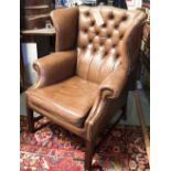 WING ARMCHAIRS, a pair, George III design buttoned tan leather each with stretchered supports.