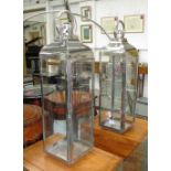 STORM LANTERNS, a pair, polished metal and glass, each 21cm W x 21cm D x 78cm H.