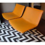 EASY CHAIRS, a pair, Italian designer style in orange leather finish on metal swivel bases,