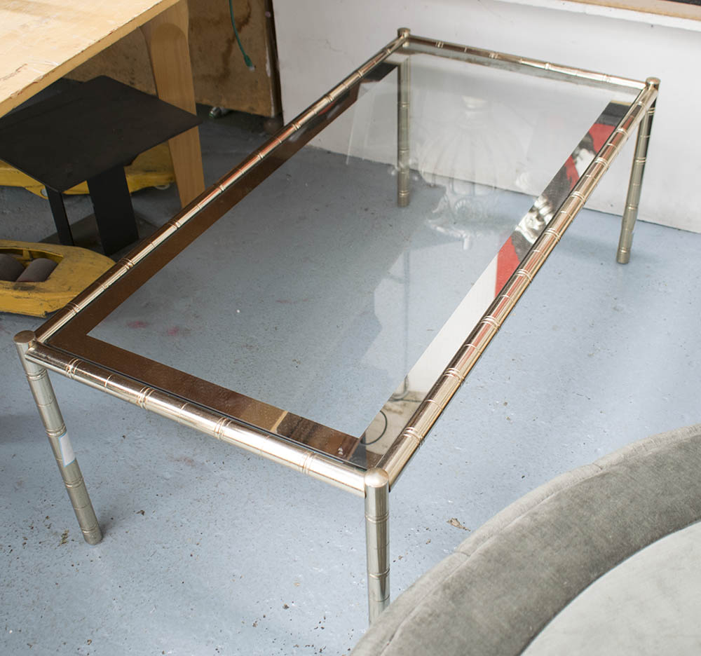 LOW TABLE, the glass top with a mirrored border on a polished metal bamboo inspired base,